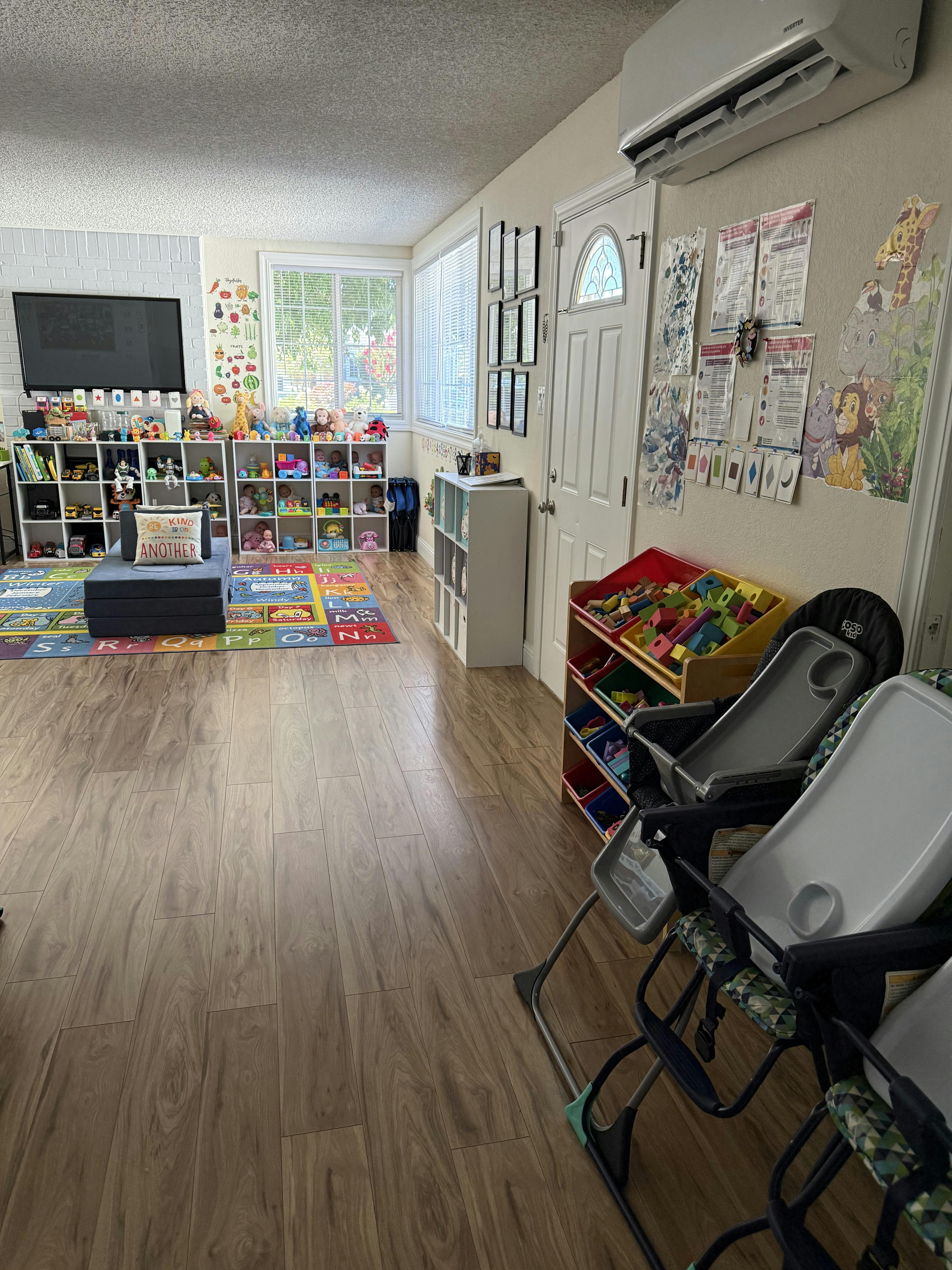 Playroom with toy shelves, colorful rug, and high chairs