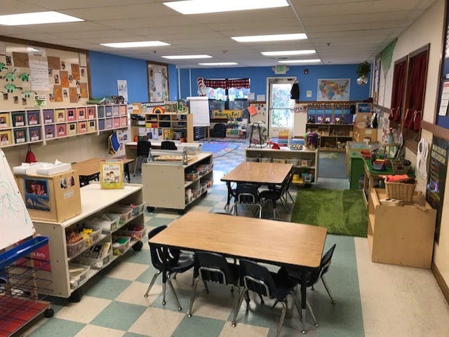 Empty colorful children's classroom with tables, chairs, and shelves