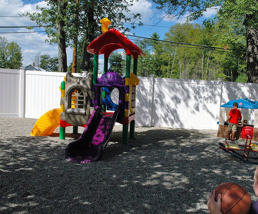 Playground with a colorful play structure and a person standing under an umbrella