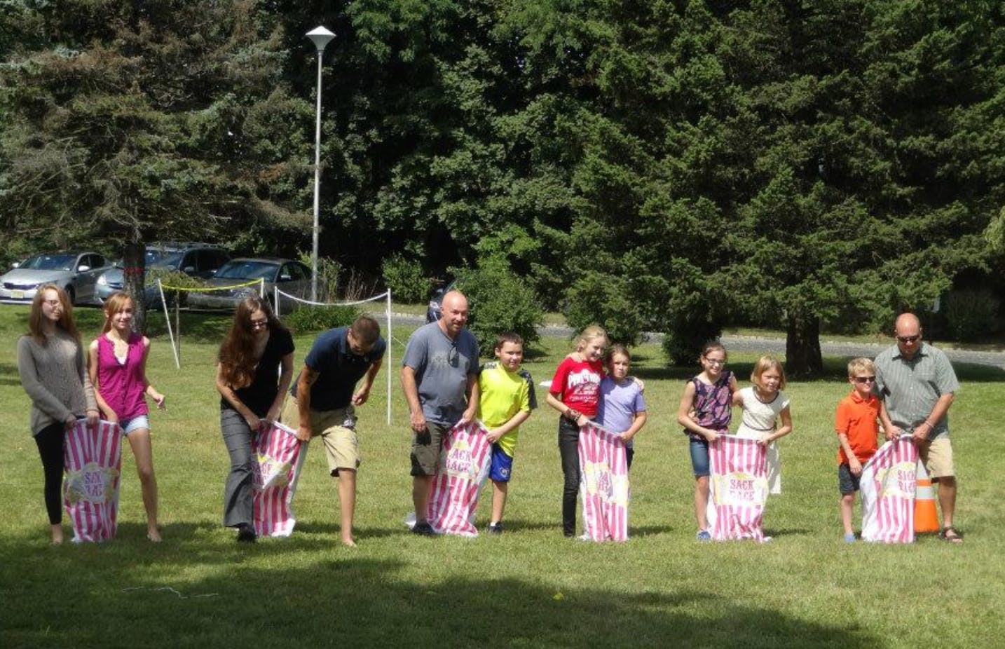 People and children in a field preparing for a sack race