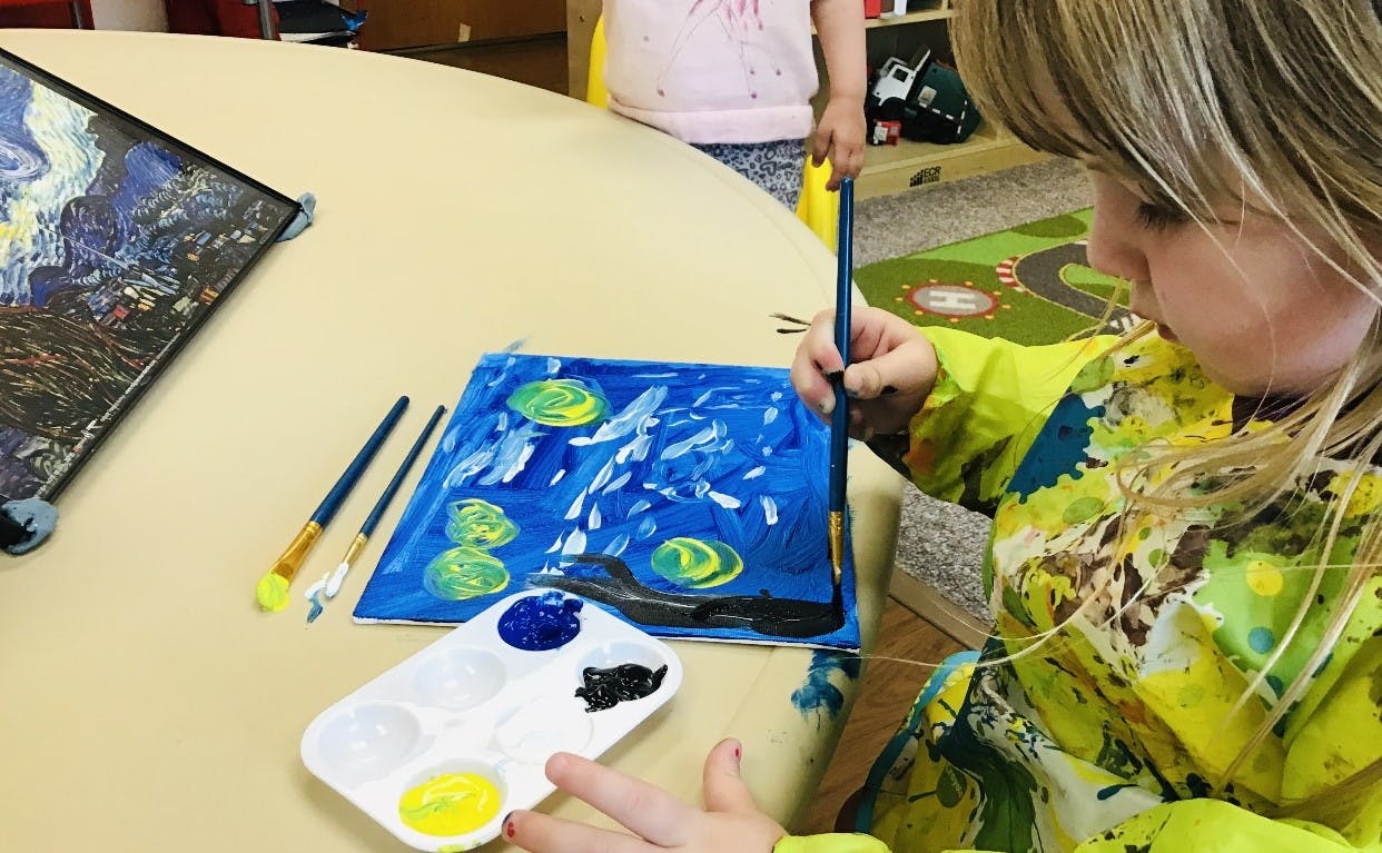 Child painting on a canvas with a brush and paint palette