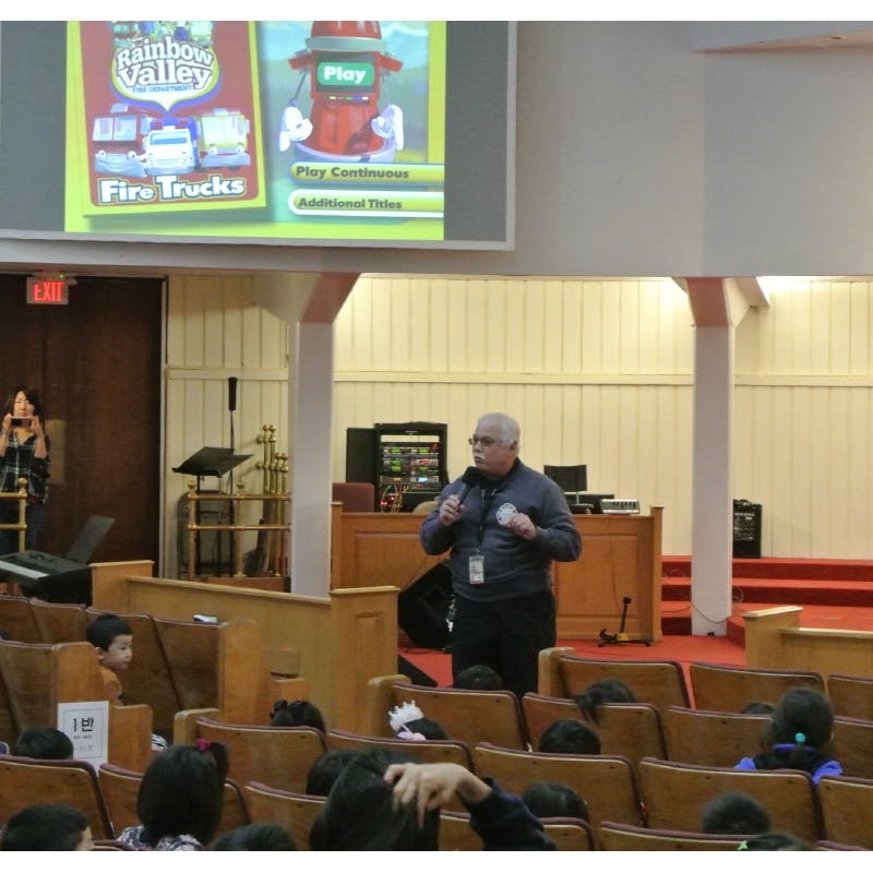 Person speaking to an audience of children in an auditorium