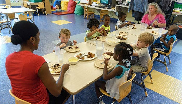 People and children eating at a table in a classroom