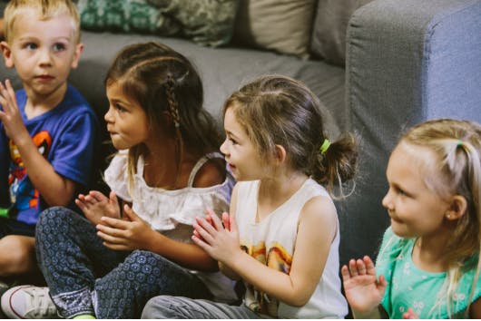 Four children sitting and clapping