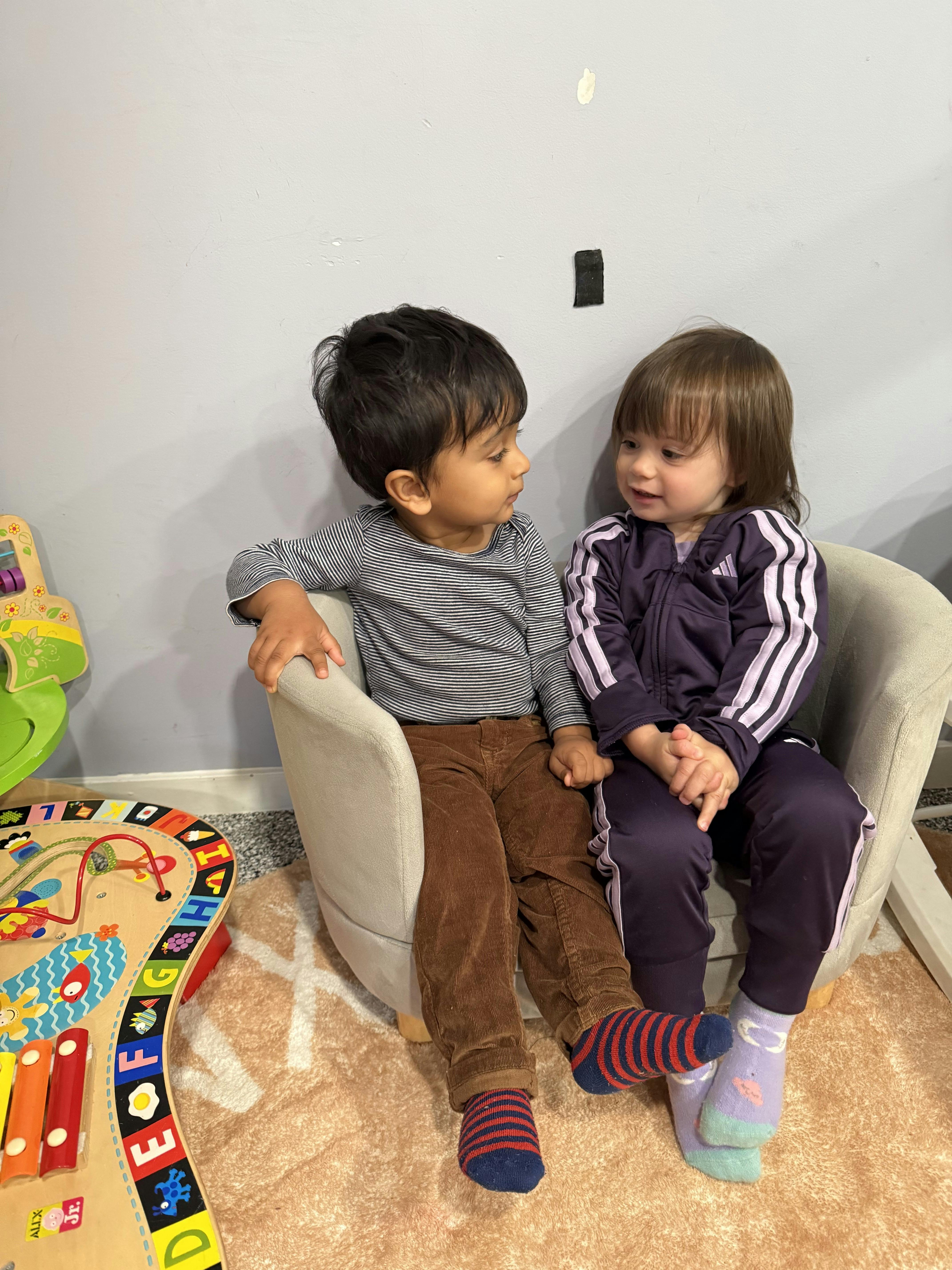 Two children sitting in chairs looking at each other