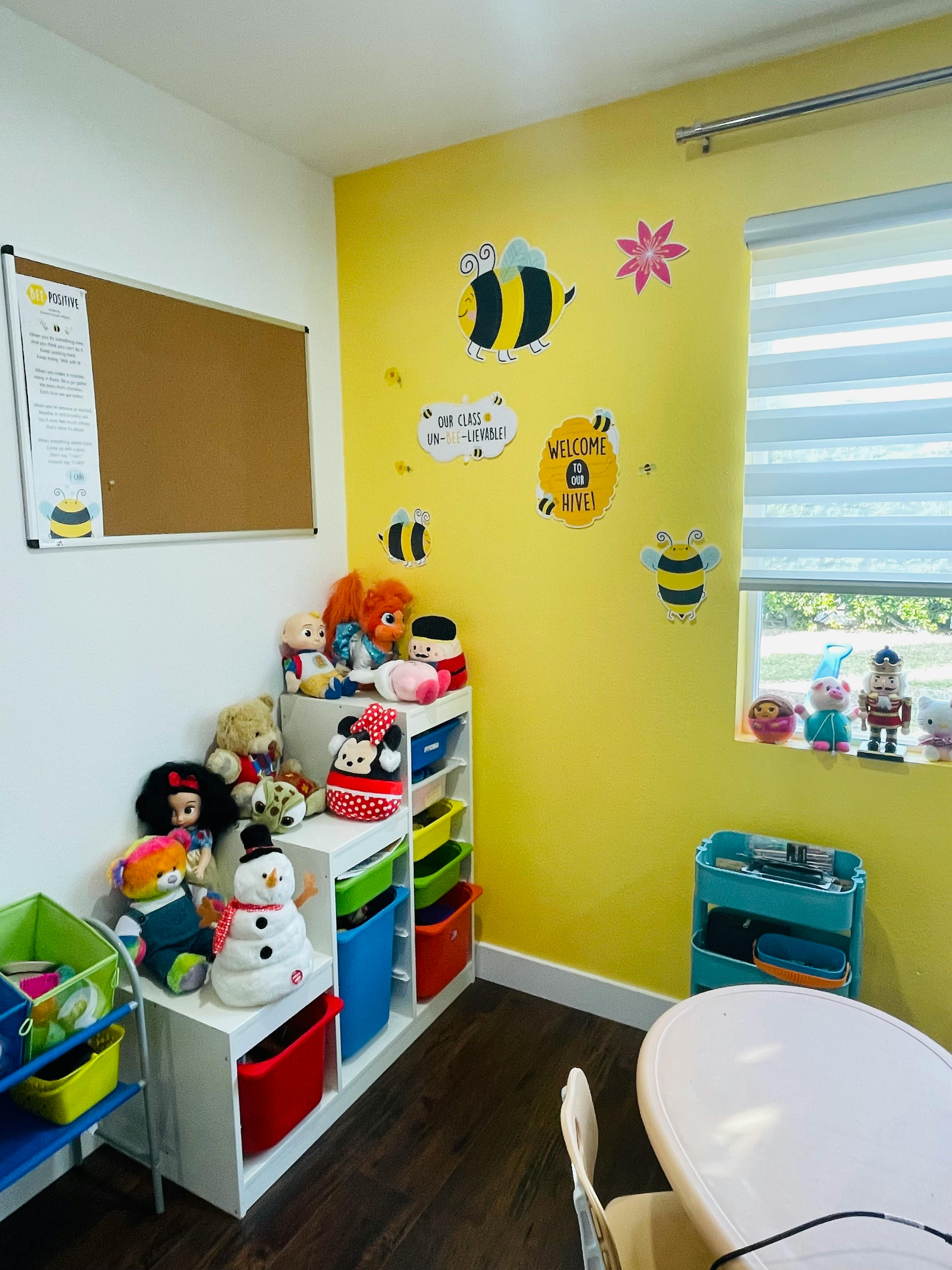 Playroom with yellow walls, toys on shelves, and a small table with chairs