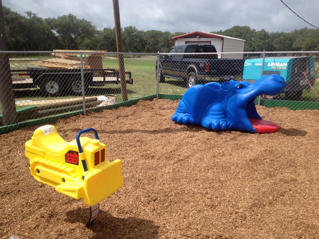 Yellow bulldozer spring rider and blue hippopotamus slide on wood chips