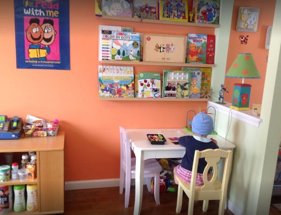 Child sitting at a small table in a room with shelves of books