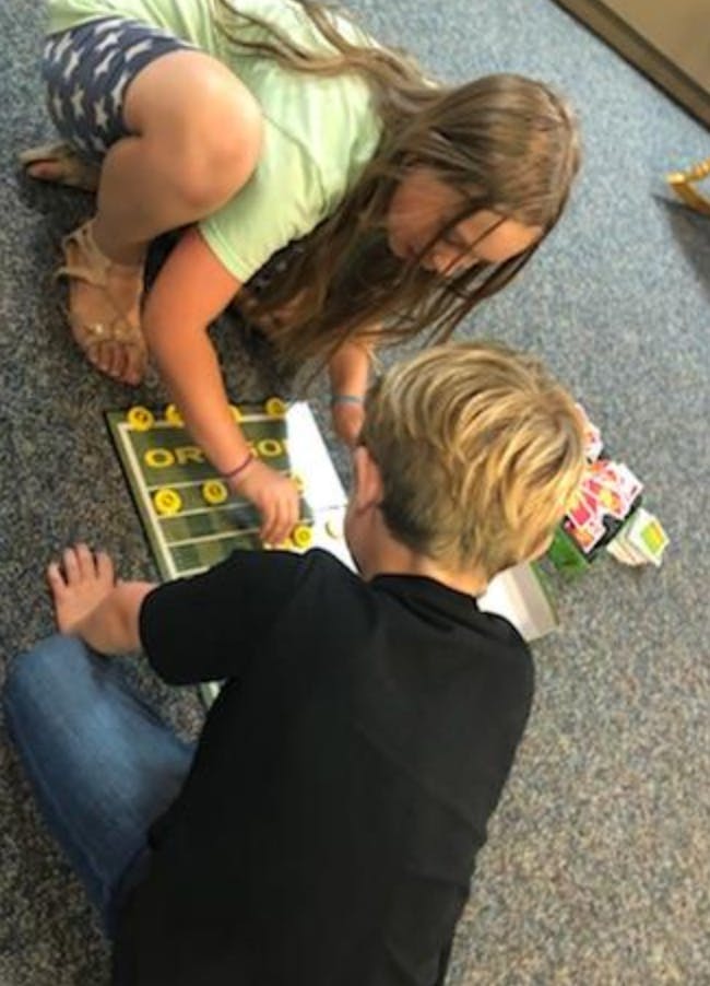 Two children playing a board game on the floor