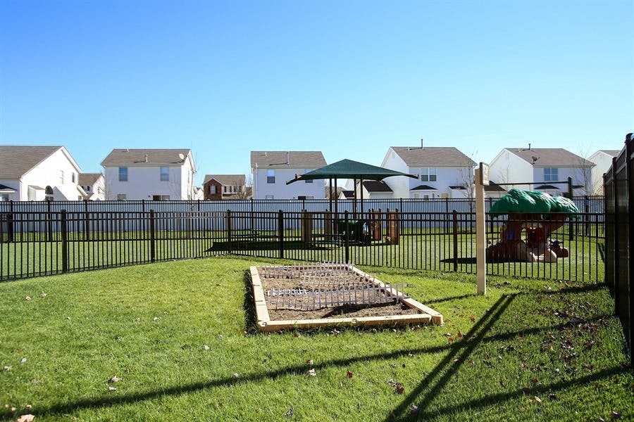 Fenced outdoor play area with a sandbox and small play structure
