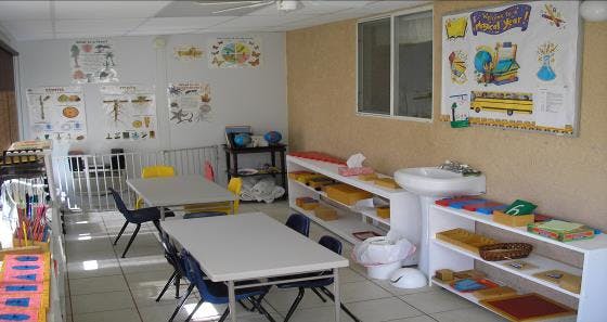 Classroom with tables, chairs, and shelves with learning materials
