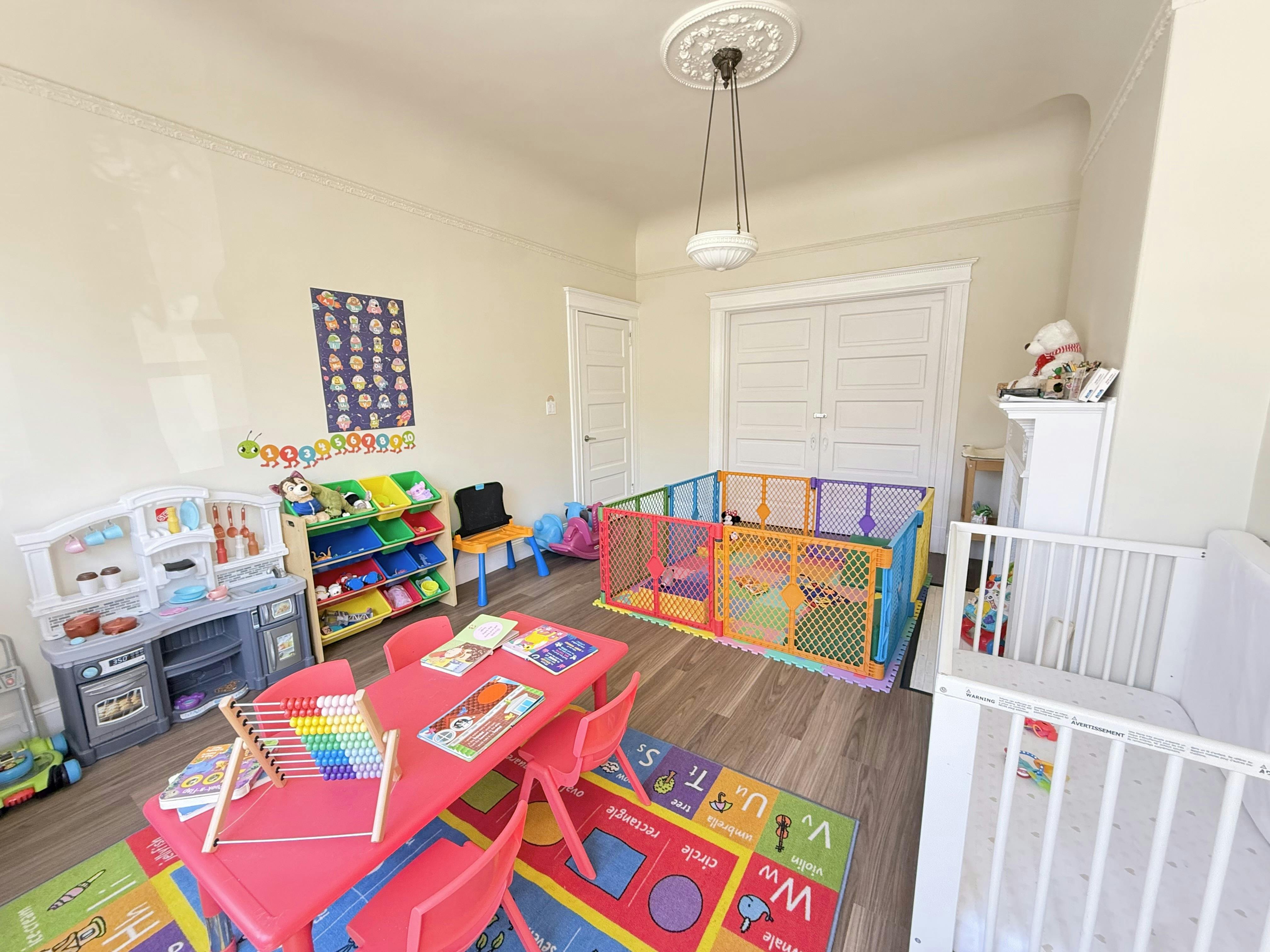 Playroom with a play kitchen, toy storage, crib, and a child-sized table and chairs