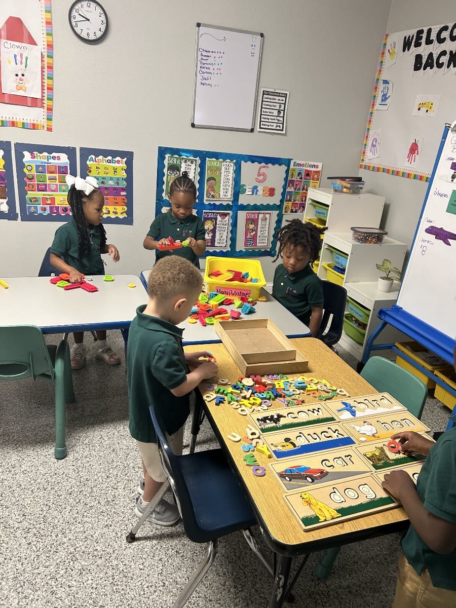 Children playing with learning toys at tables in a classroom
