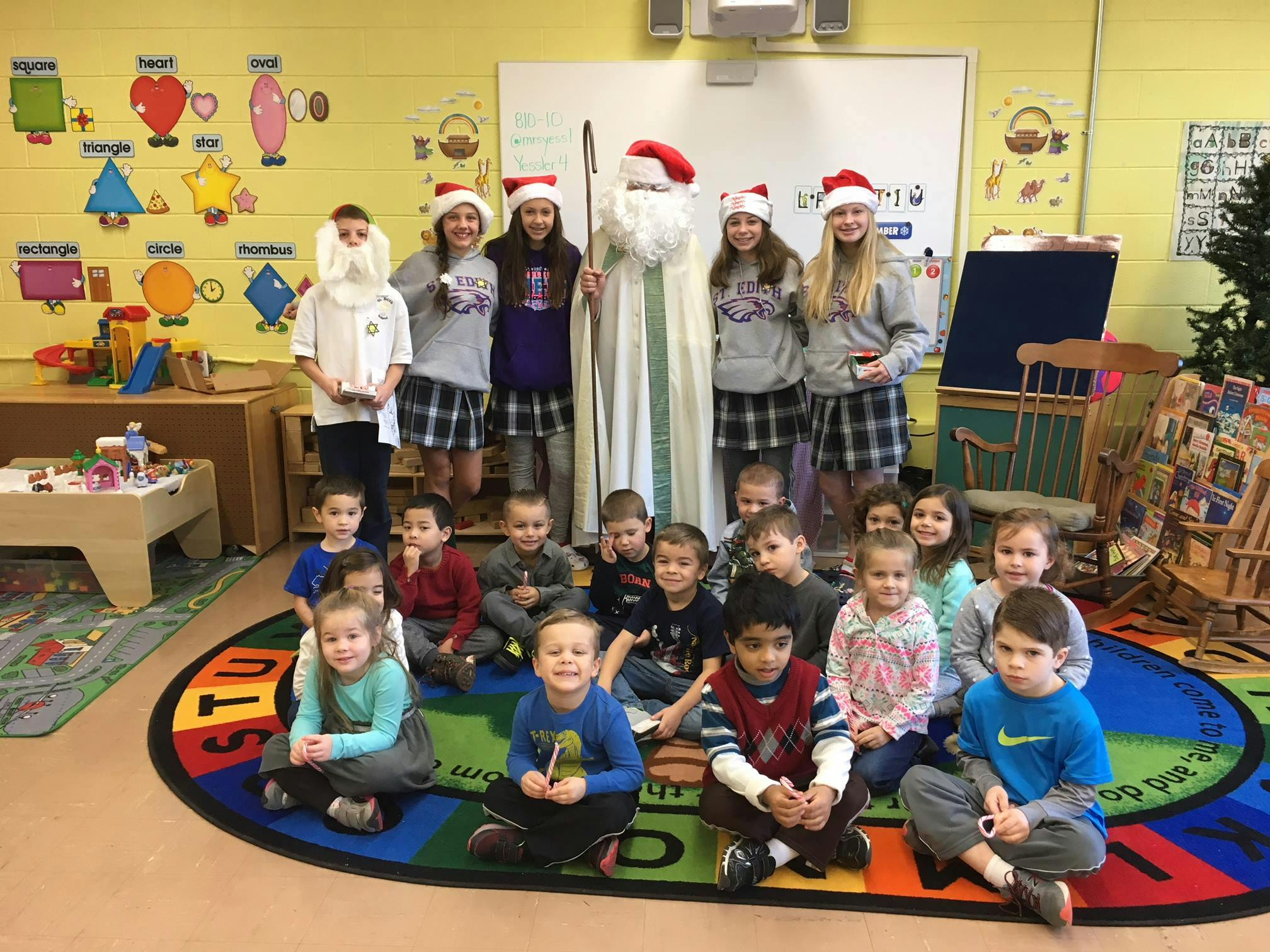 Group of children and teens with a person dressed as Santa Claus in a classroom