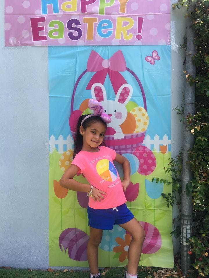 Child posing in front of a Happy Easter banner