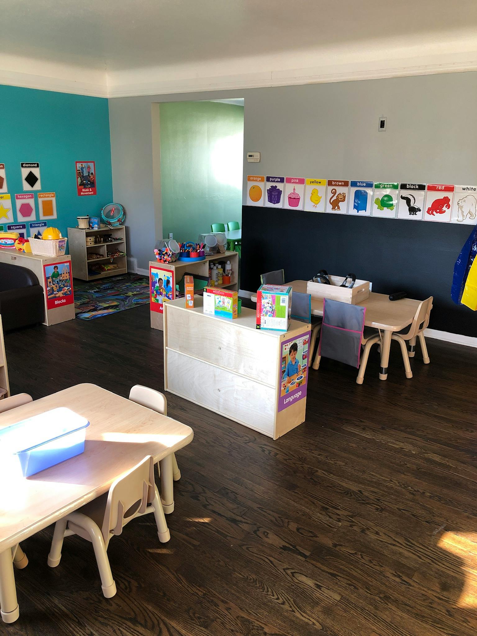 Classroom with small tables and chairs, storage units, and colorful wall decorations