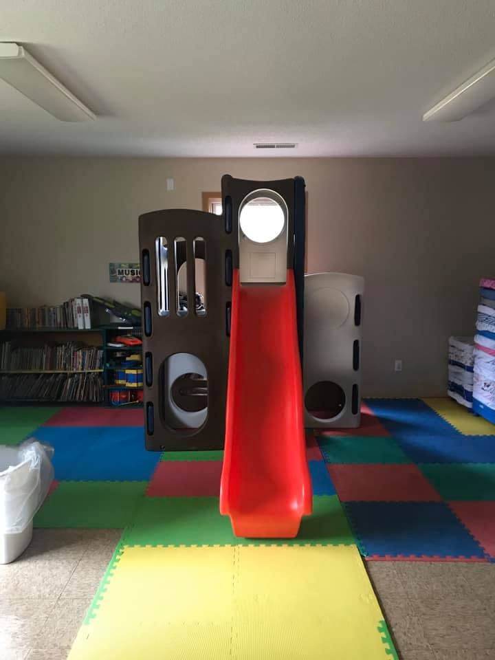 Indoor playground with a red slide and colorful floor mats