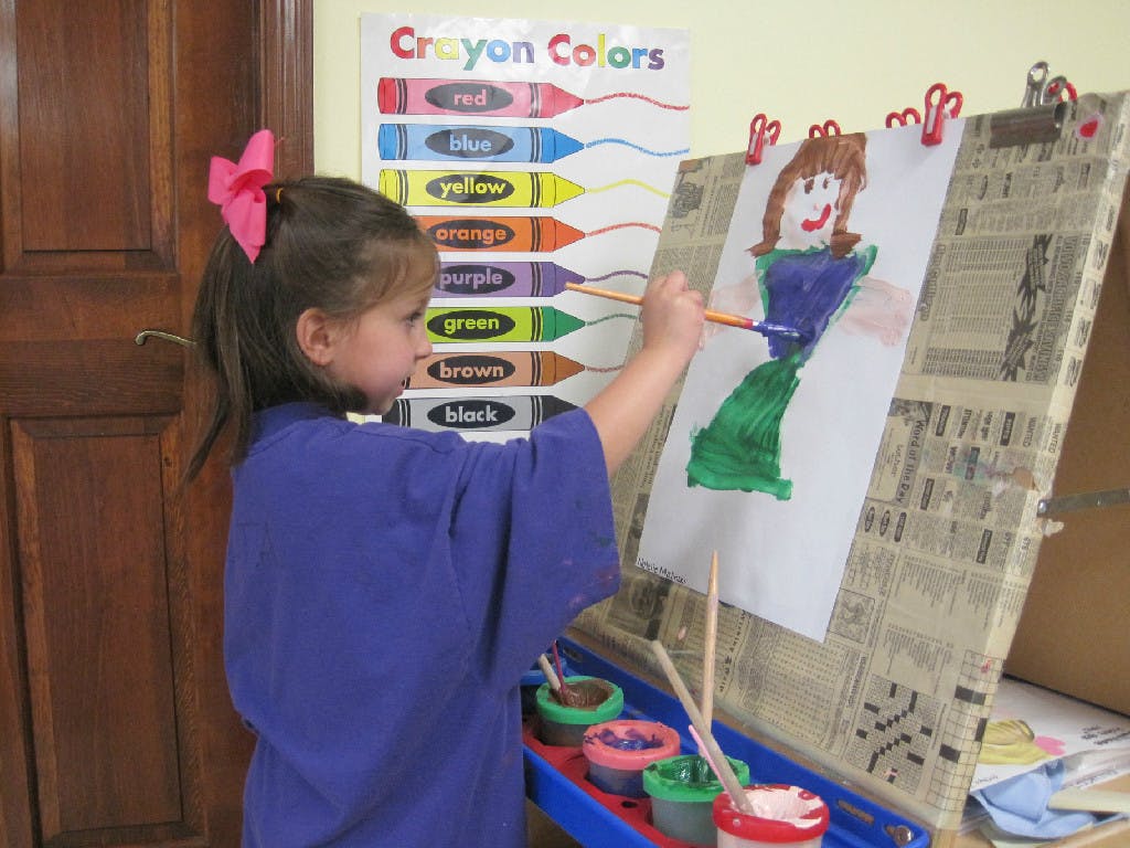 Child painting a figure on an easel