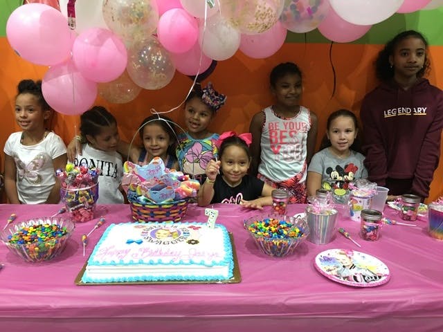 Children gathered around a table with a cake and candy