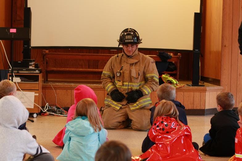 Firefighter kneeling in front of children