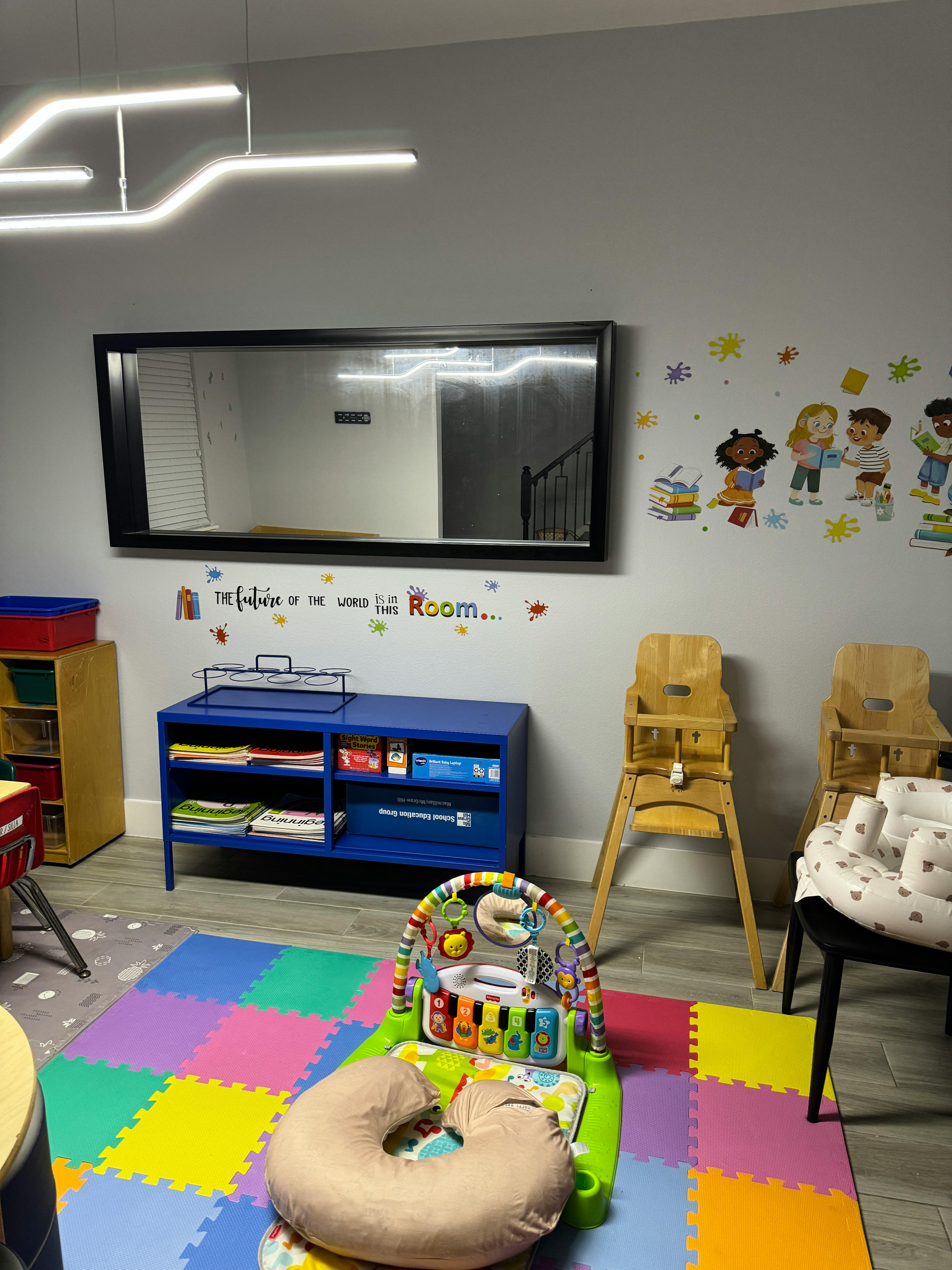 Childcare room with play mat, infant activity gym, and high chairs