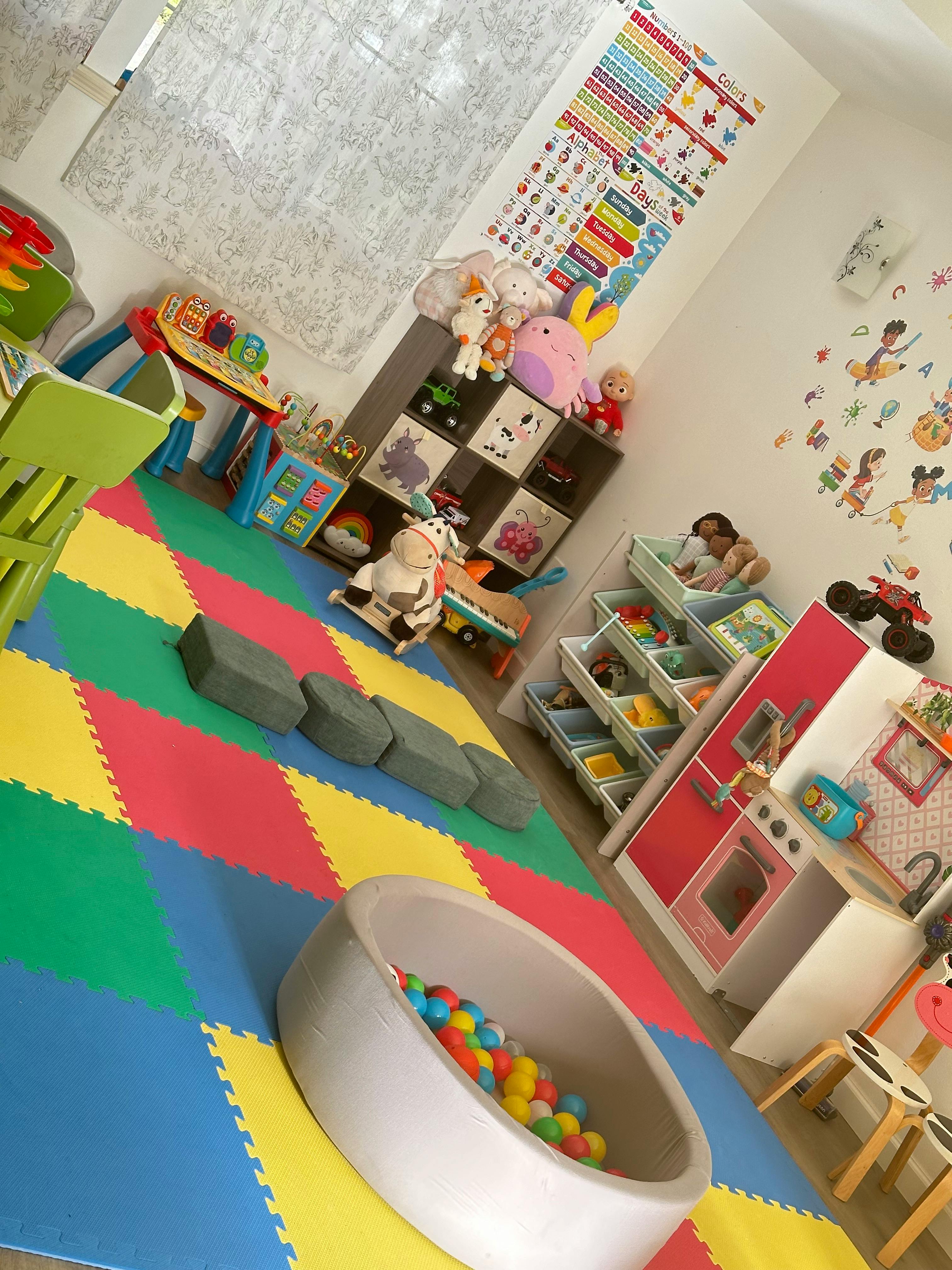 Playroom with colorful floor mats, toys, and a ball pit