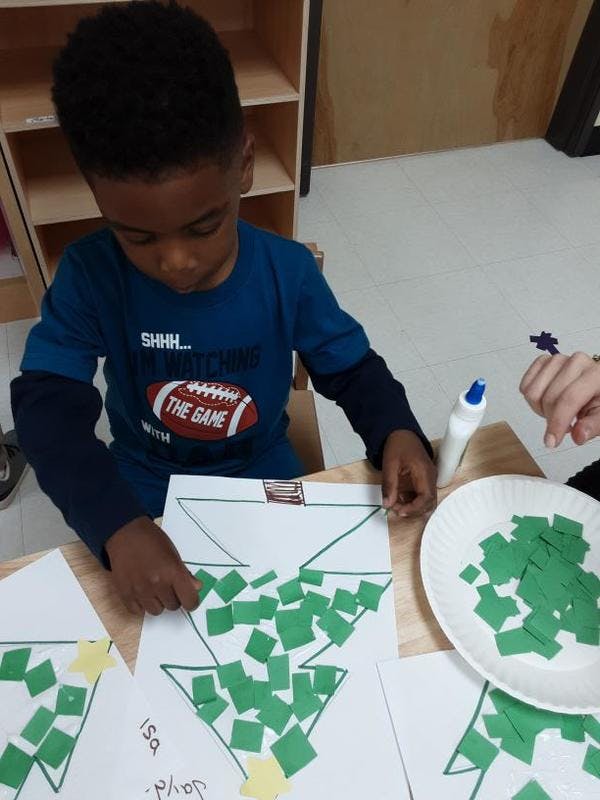 Child making a craft with green paper squares