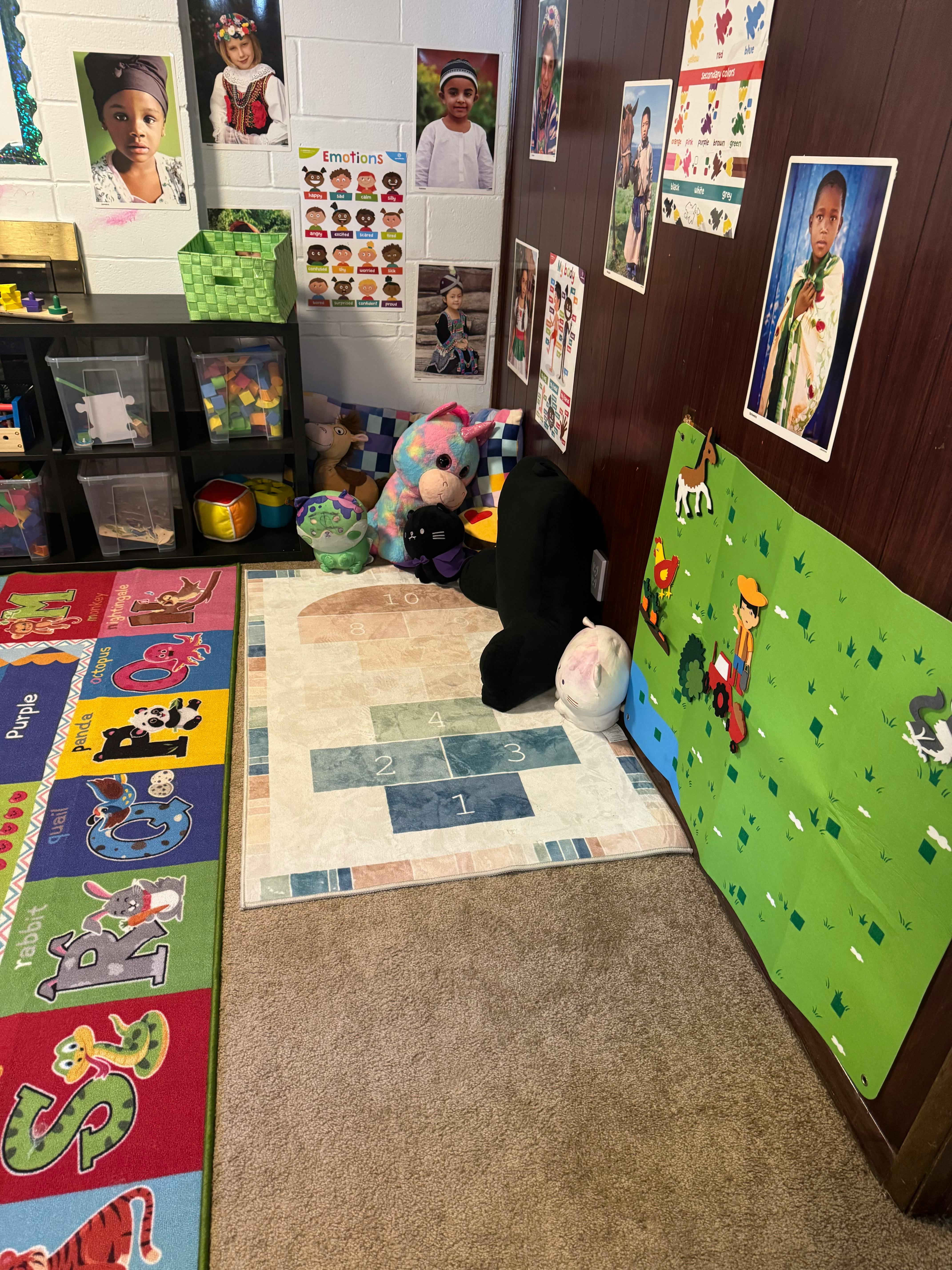 Playroom with colorful rugs, stuffed animals, and photos on the wall