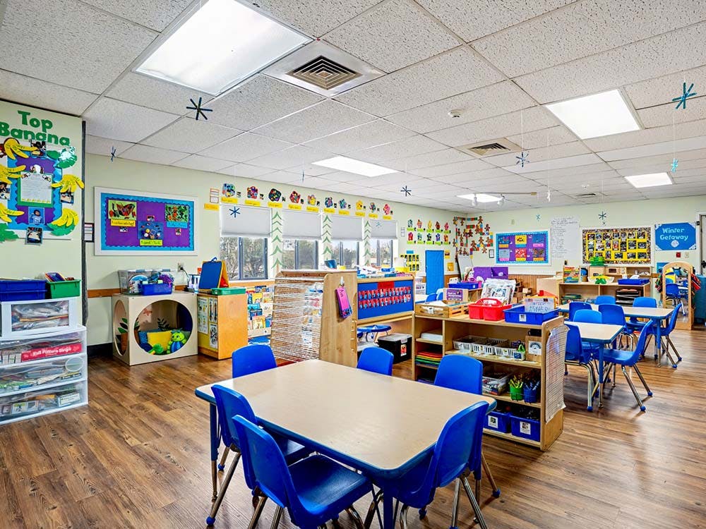 Classroom with tables, blue chairs, and children's artwork on the walls