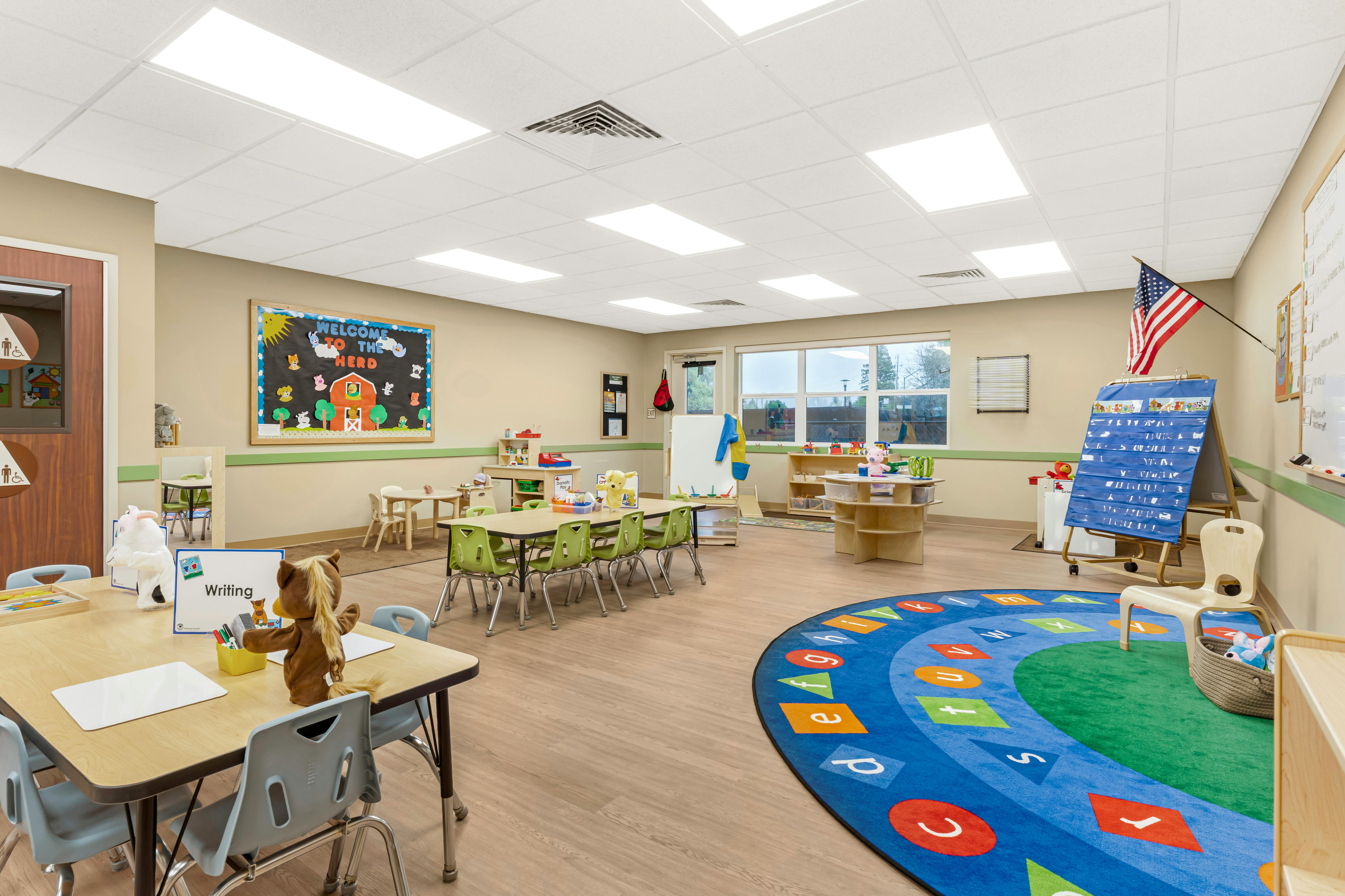 An empty early education classroom with small tables and chairs