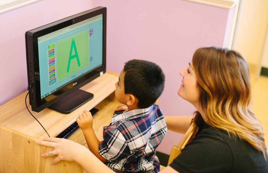 Adult and child looking at a computer screen with a large letter A
