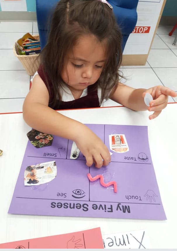 Child playing with a purple "My Five Senses" activity mat