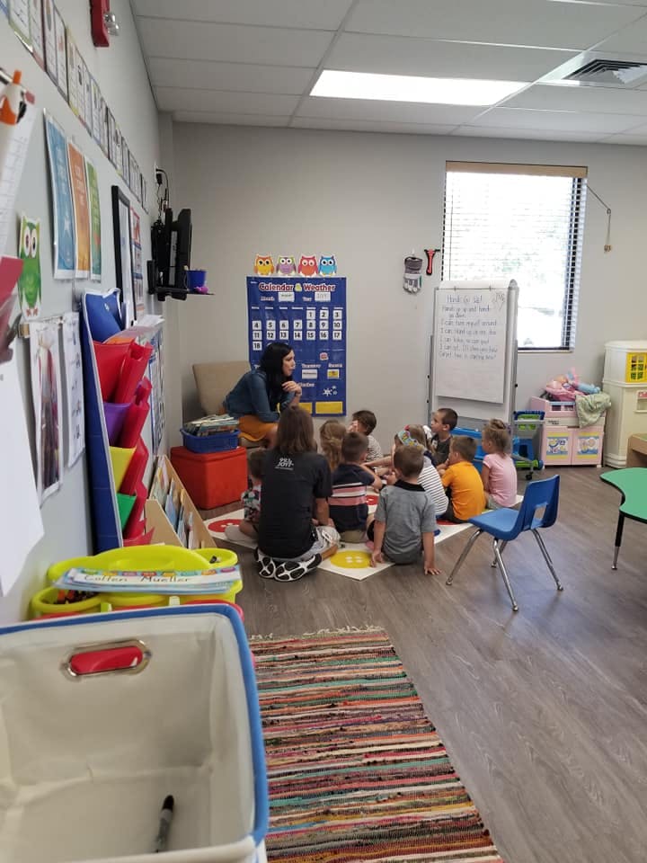 Adults and children sitting on the floor in a classroom