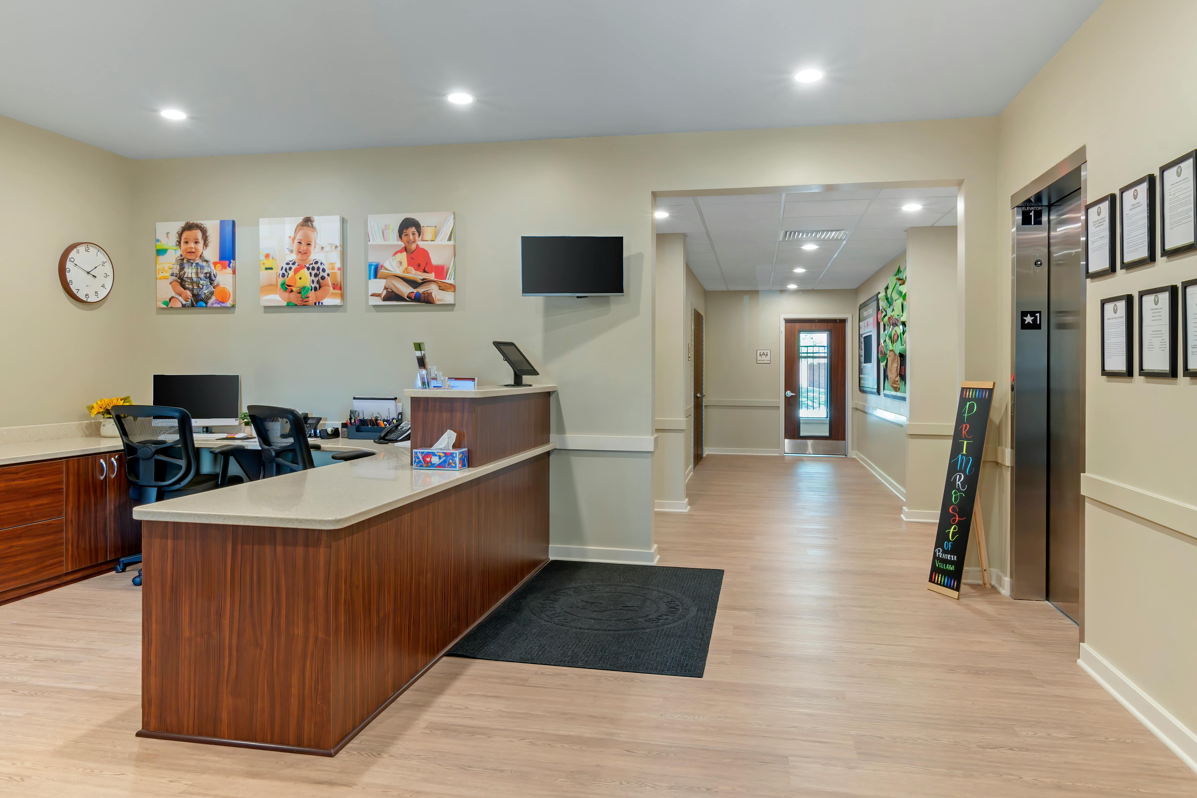 Reception area with a wooden desk, computer monitors, and chairs
