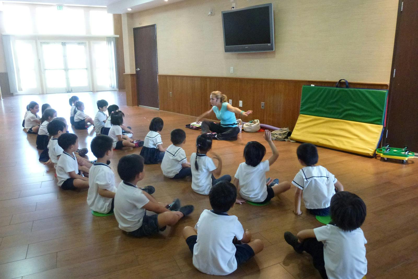 Adult leading a group of children sitting on the floor in a classroom