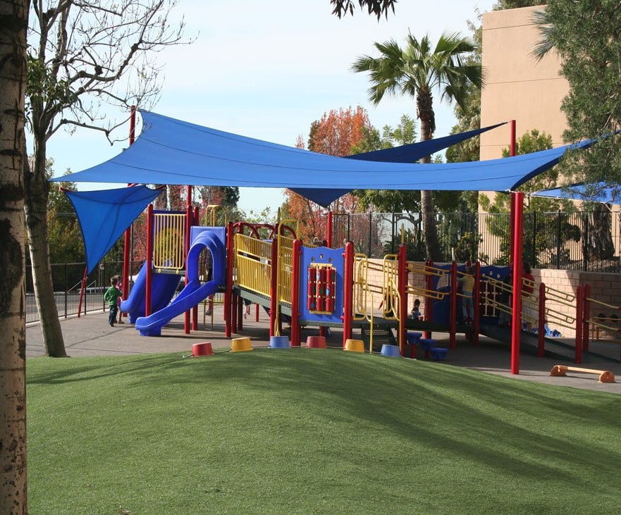 Playground with blue shade sails over colorful play structures