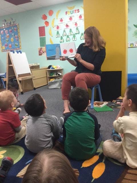 Person reading a book to children in a classroom
