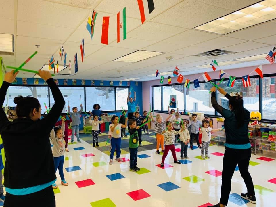 Two adults leading a group of children in an activity in a classroom