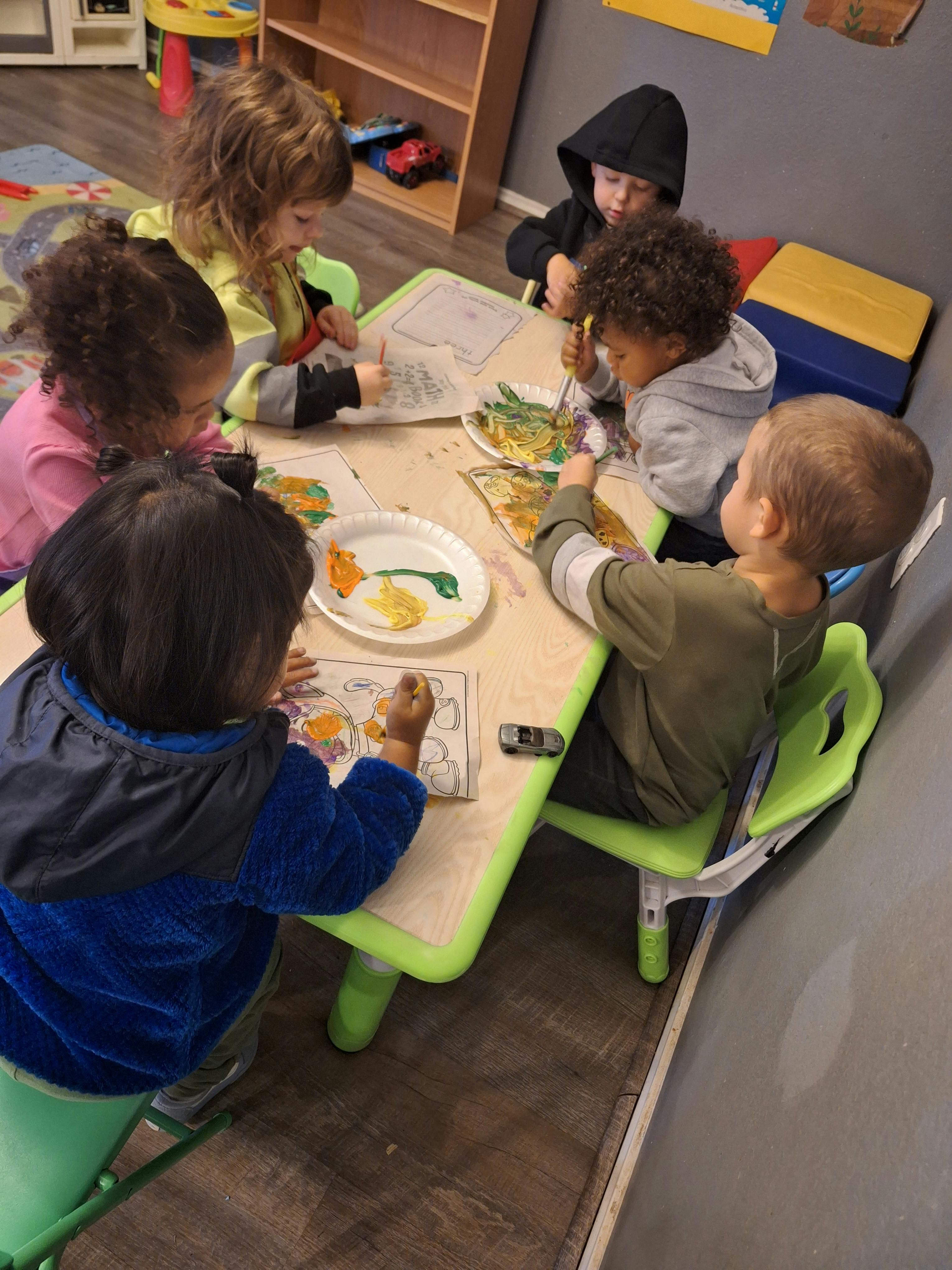 Children painting at a table in a classroom