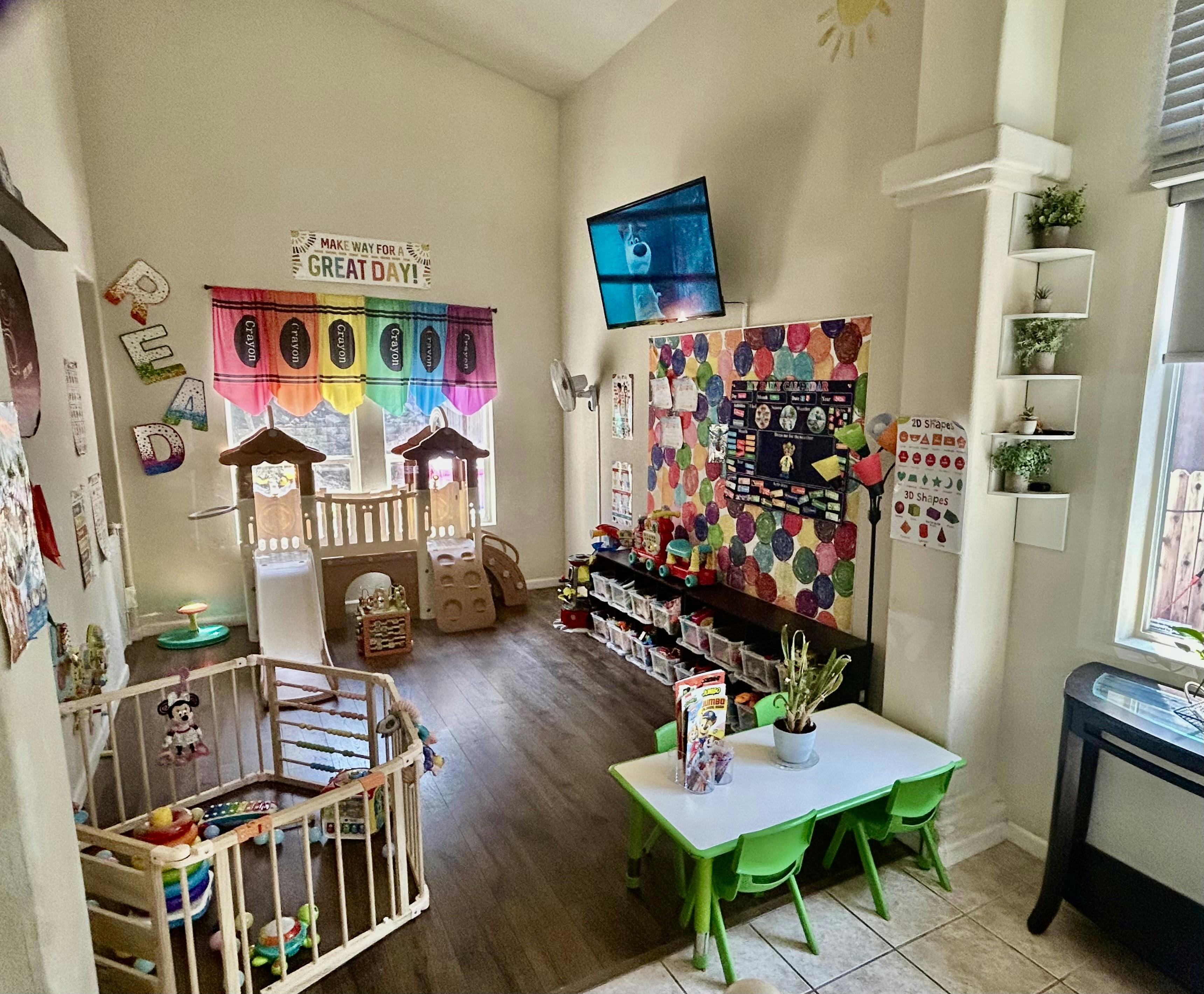 Children's playroom with various toys, slides, a playpen, and a small table with chairs
