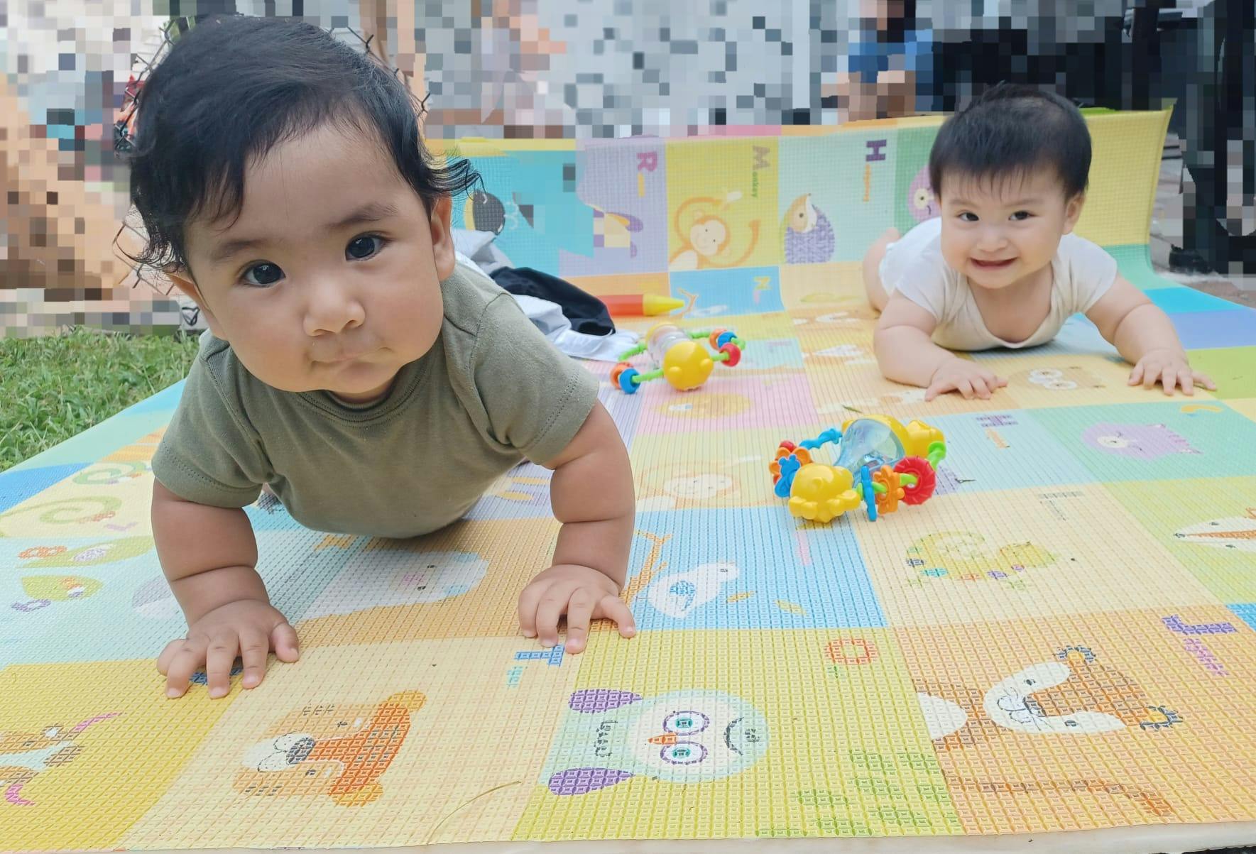 Two children crawling on a colorful playmat