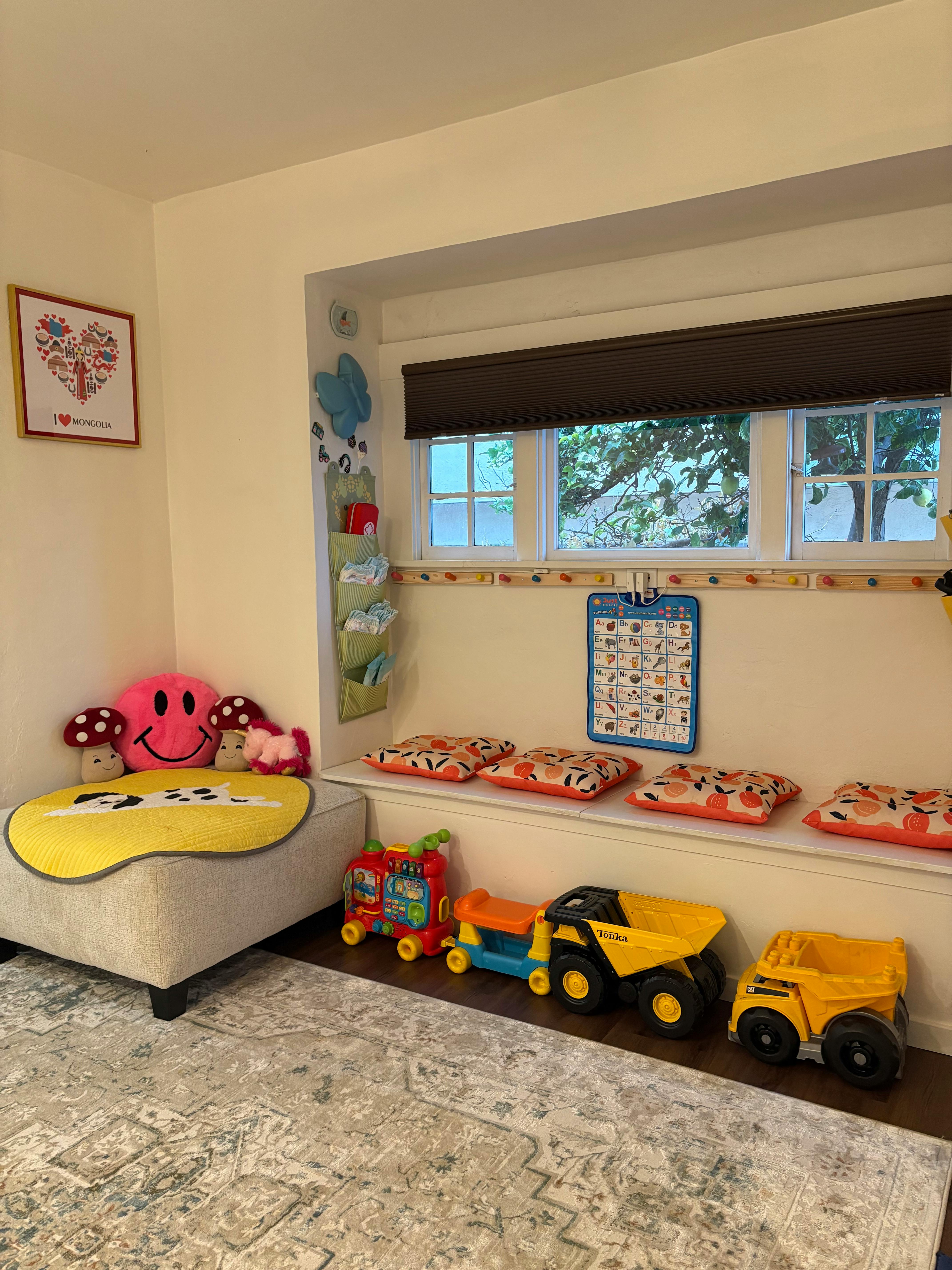 Playroom with window seat, pillows, and toy trucks