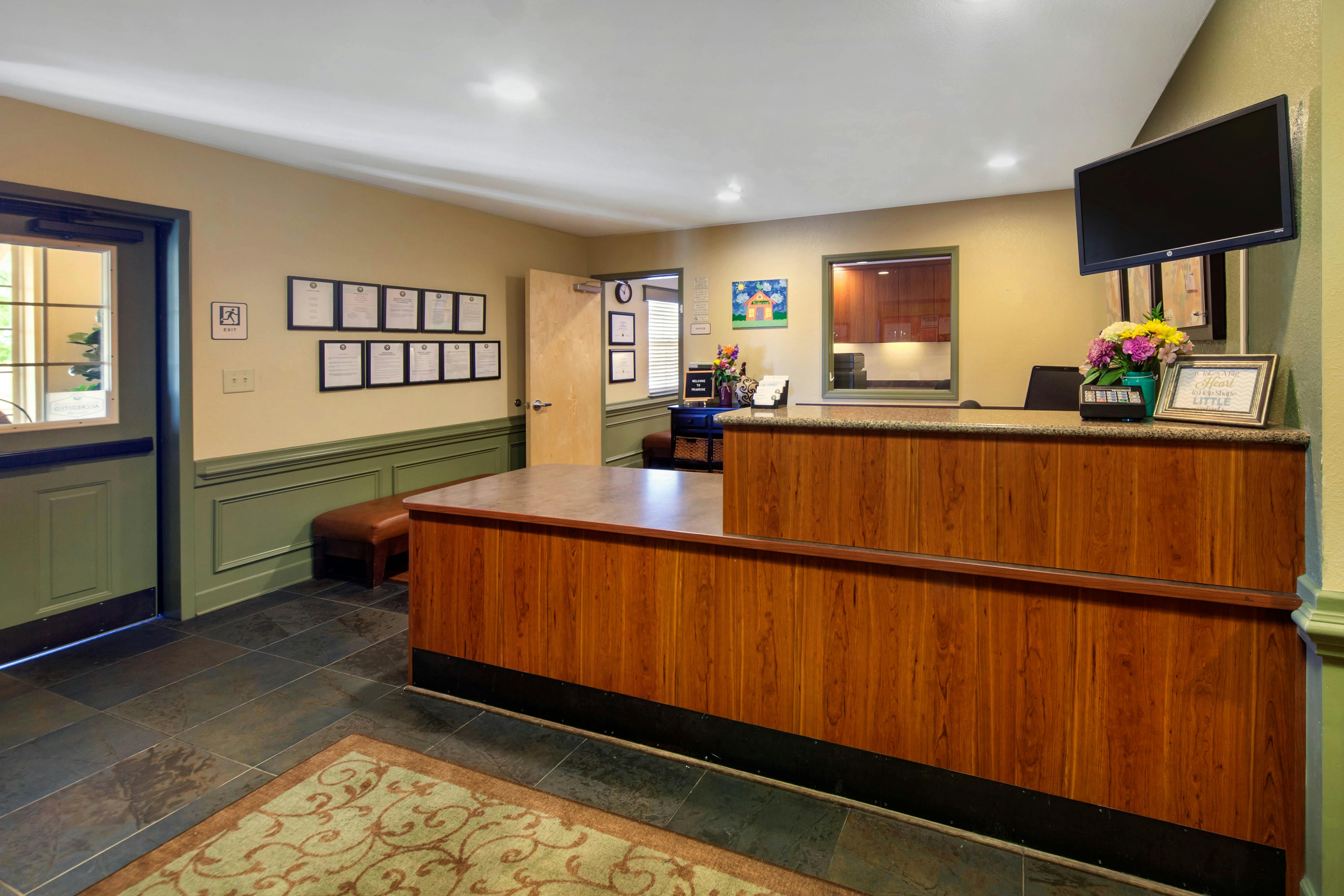 Reception desk with wood paneling and a large TV on the wall