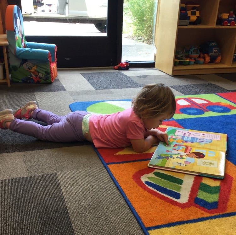 Child lying on a rug reading a book