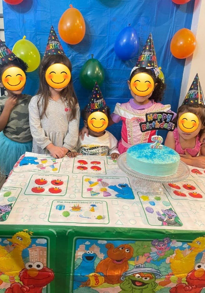 Children wearing party hats around a table with a birthday cake