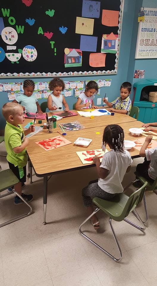 Children painting at a table in a classroom