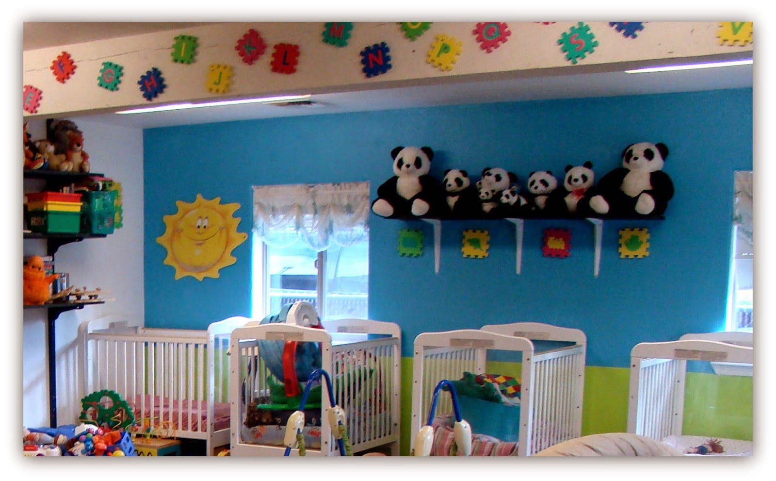 Nursery room with multiple cribs and panda stuffed animals on a shelf