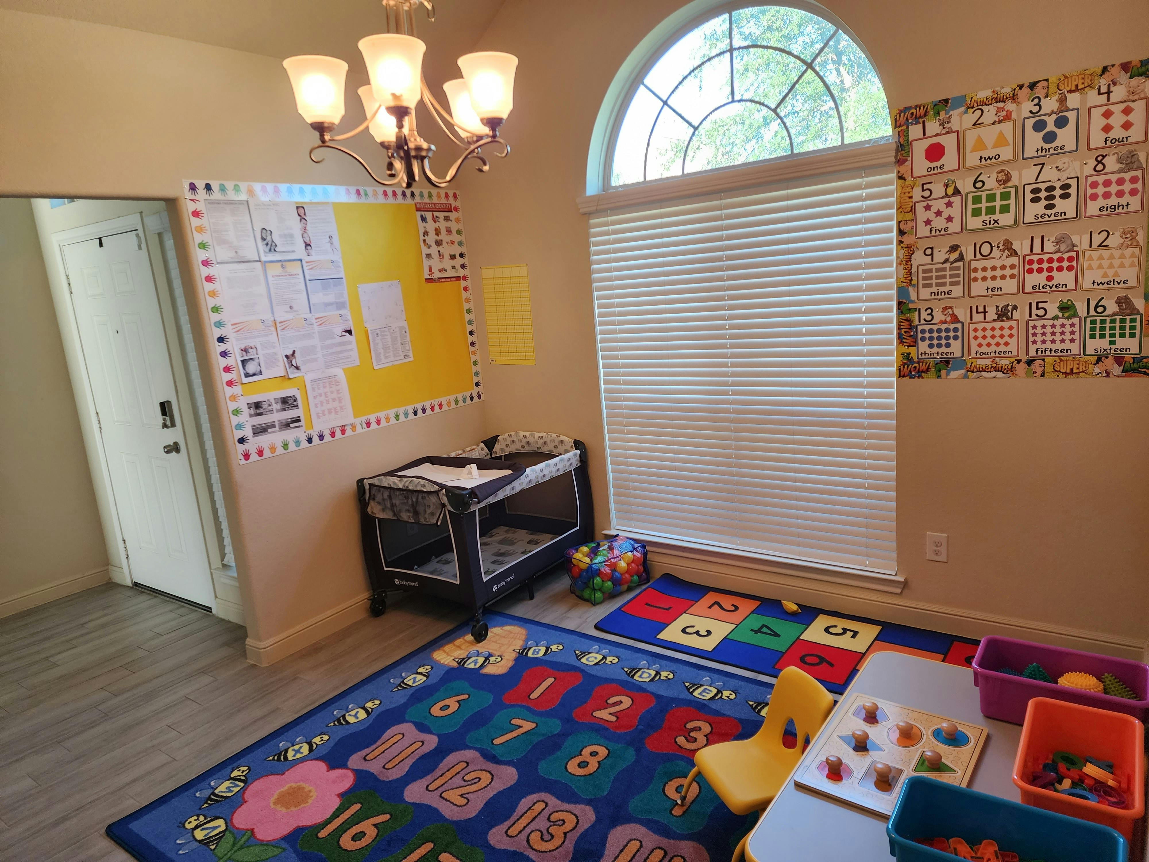Child's play area with colorful rugs, a crib, and a small table with toys