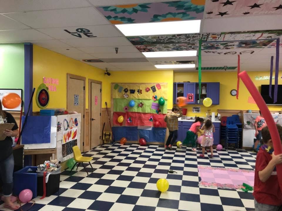 People and children in a colorful room with a checkered floor