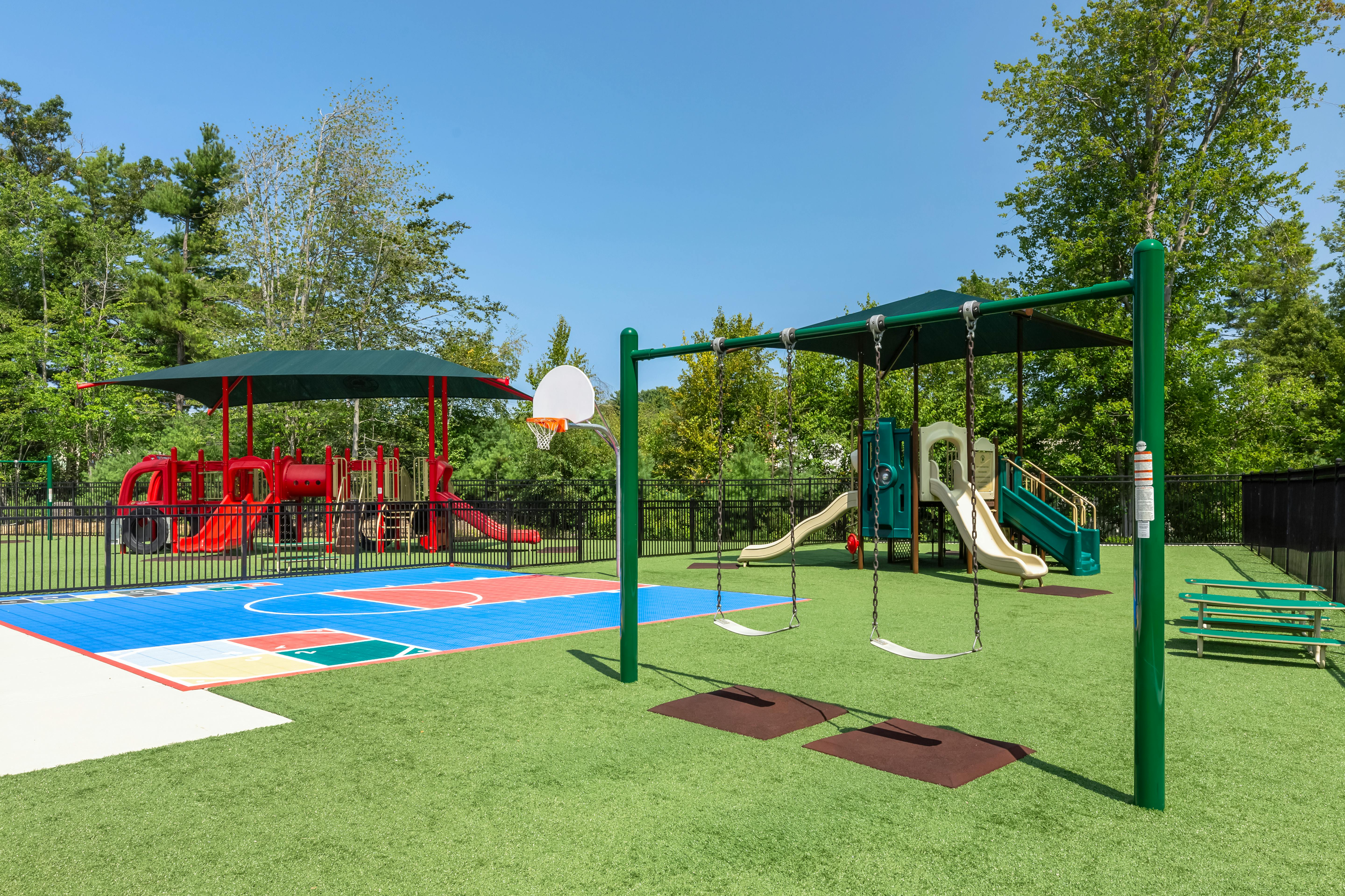 Playground with swings, slides, a basketball hoop, and a colorful court